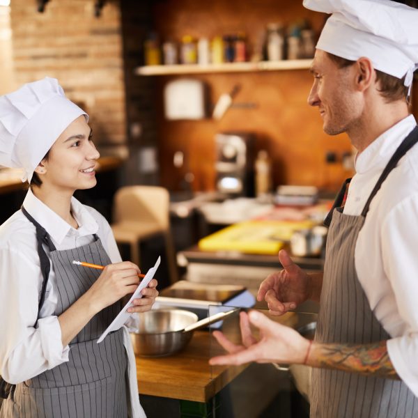 Side view portrait of two professional chefs discussing menu in restaurant, copy space